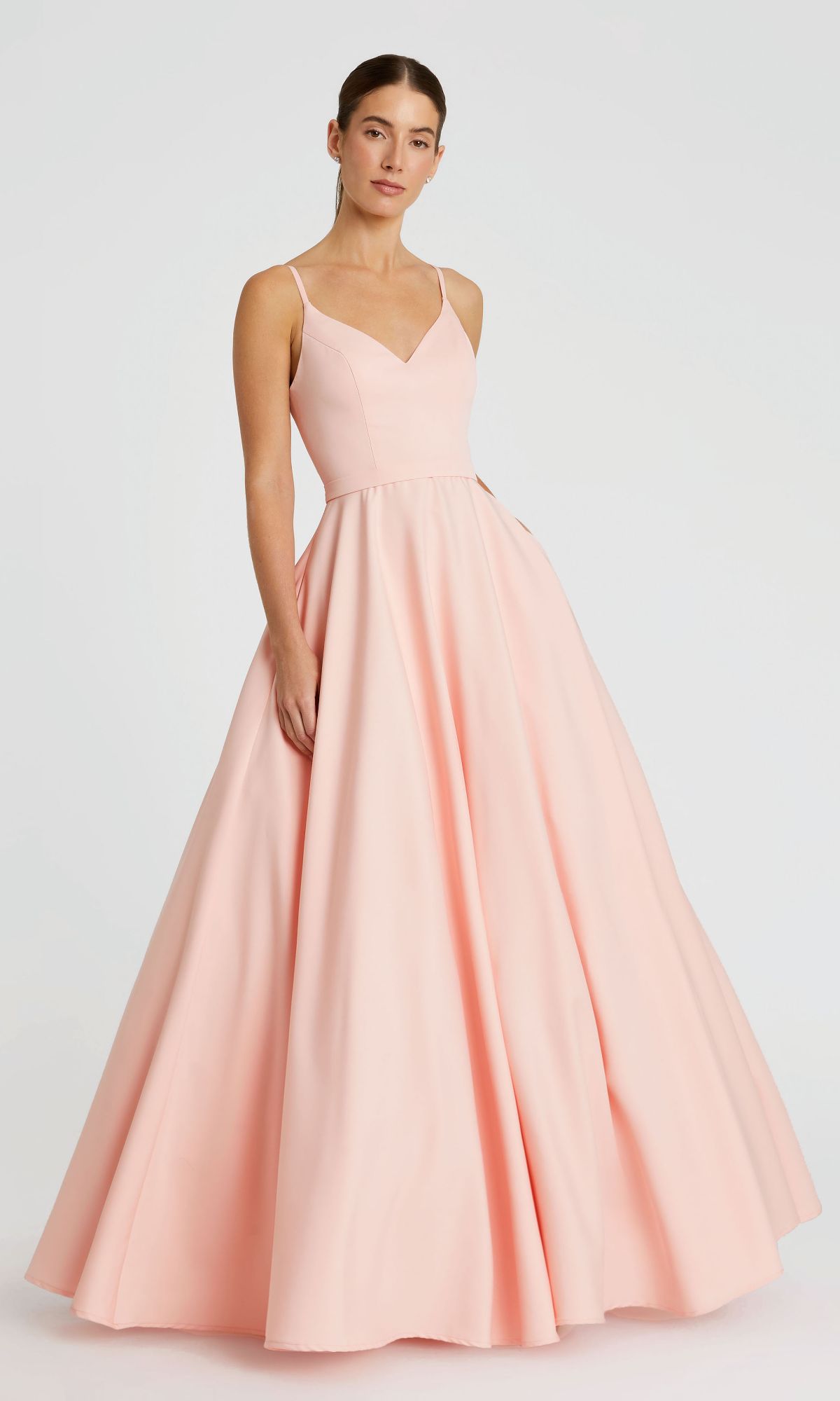 A woman wears the Mac Duggal 48855 Classic Long A-Line Formal Dress, a floor-length pale pink gown with thin straps and a fitted bodice, standing against a plain light background.